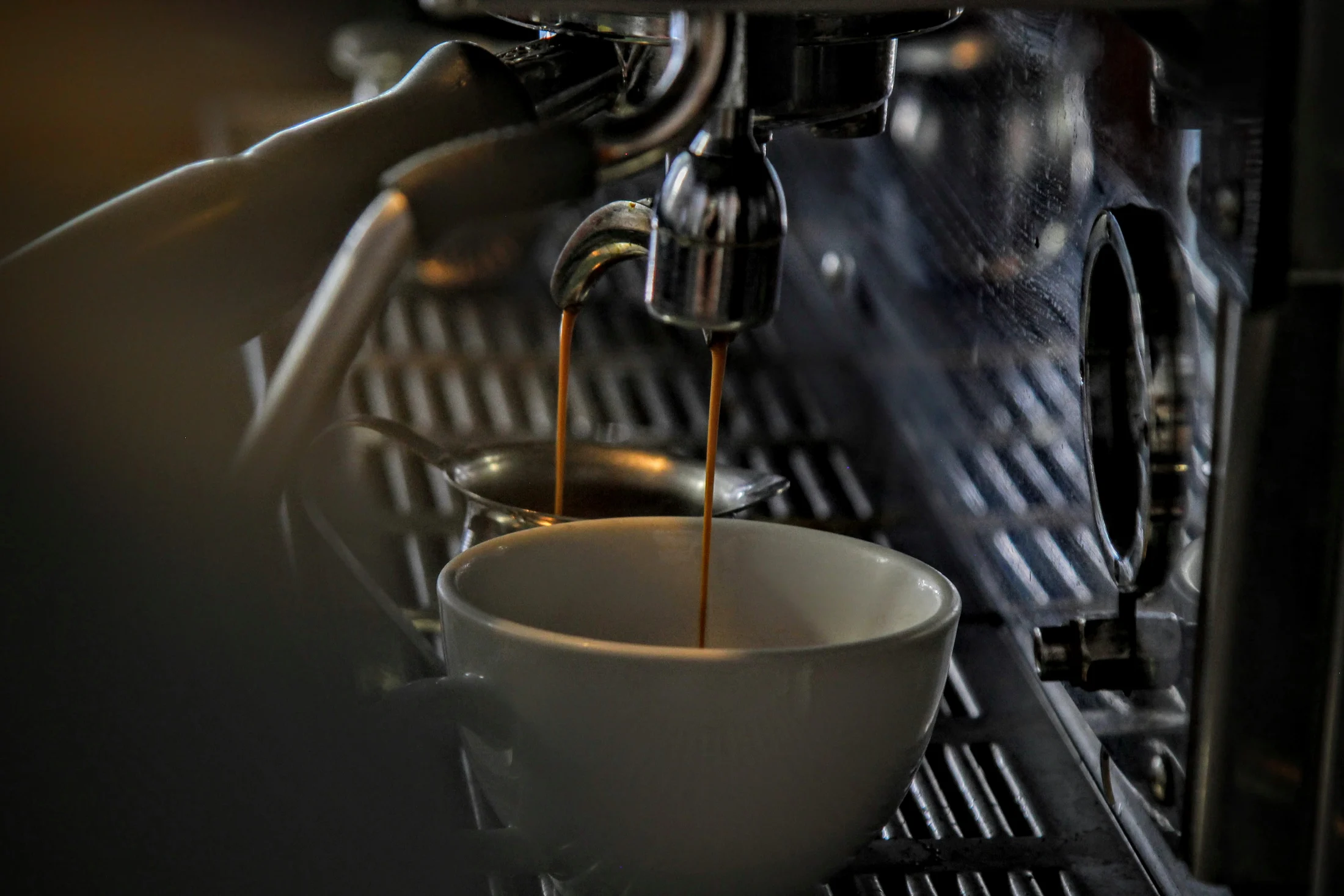 Fotografia real de espresso sendo extraído em uma xícara branca